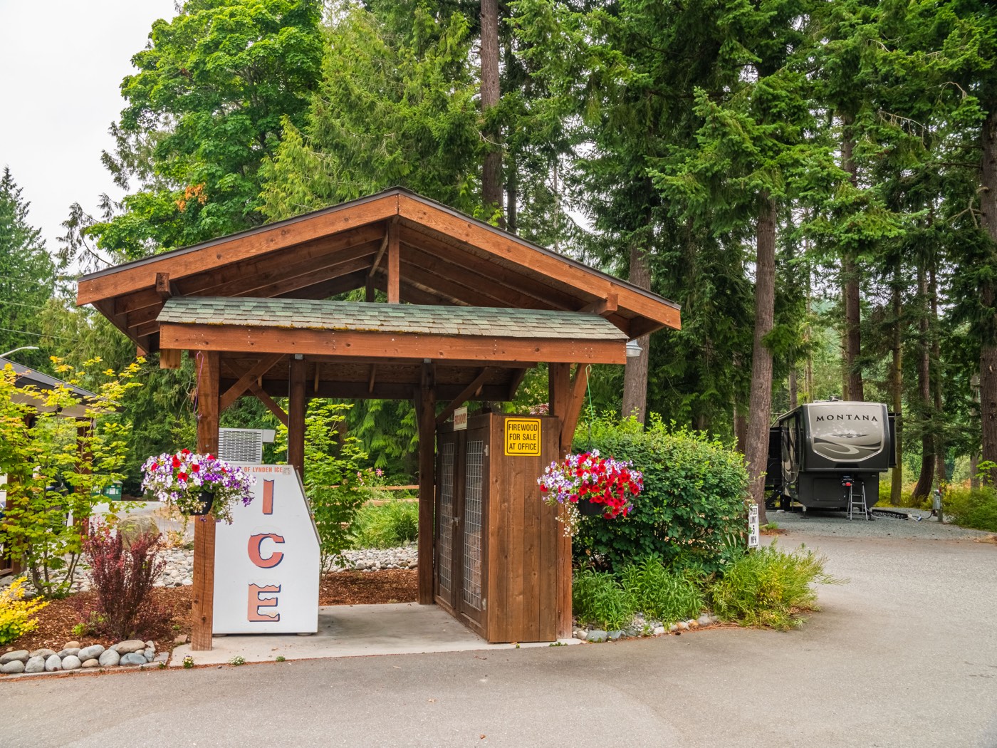 Timber entry pavilion with flower beds at Pioneer Trails RV Park